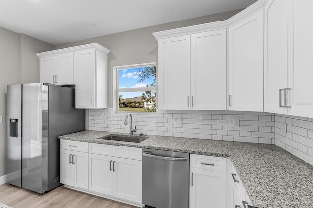 kitchen with white cabinetry, sink, light stone counters, and stainless steel appliances