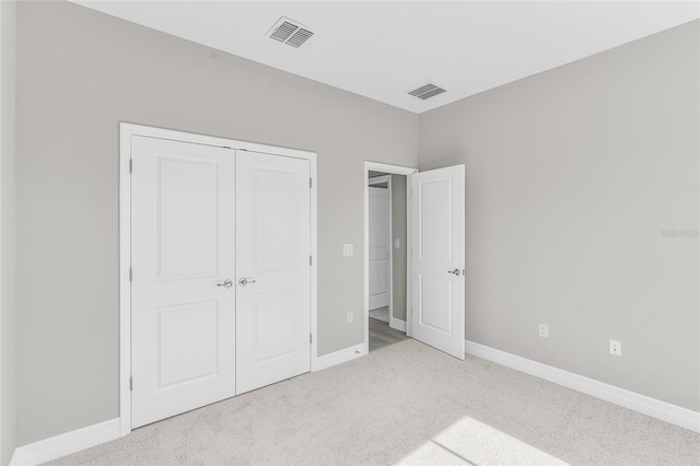 unfurnished bedroom with light colored carpet and a closet