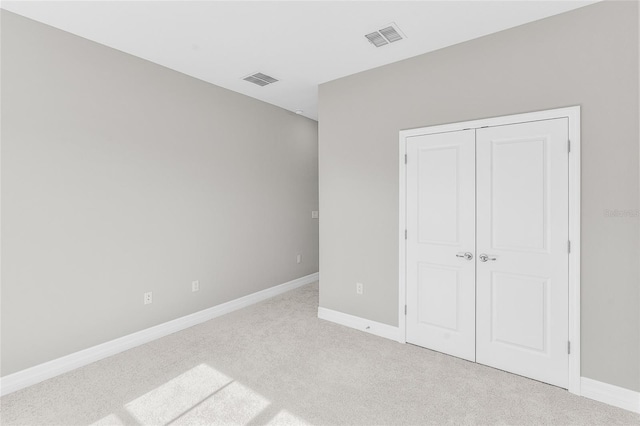 unfurnished bedroom with light carpet and a closet