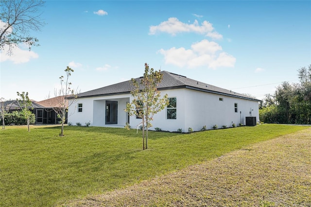 rear view of property featuring a lawn and central air condition unit