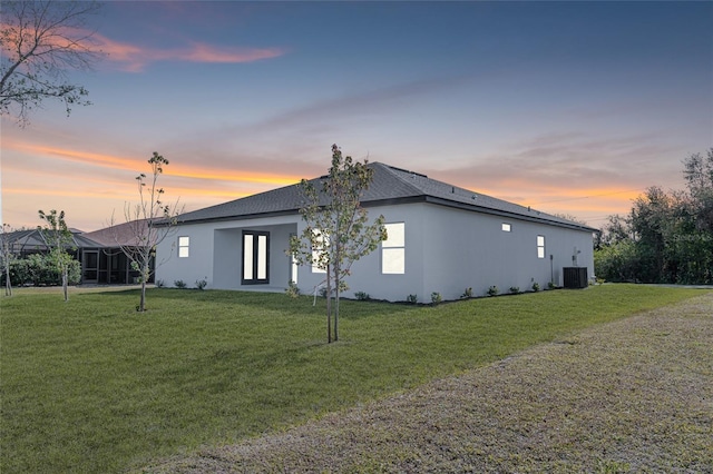 property exterior at dusk featuring a yard and central air condition unit