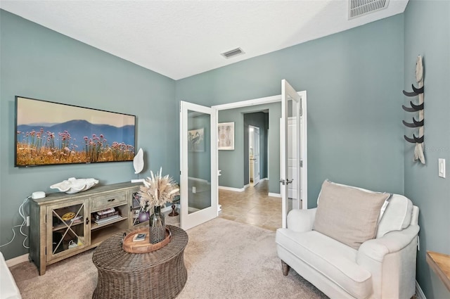 carpeted living area with tile patterned flooring, visible vents, french doors, and baseboards