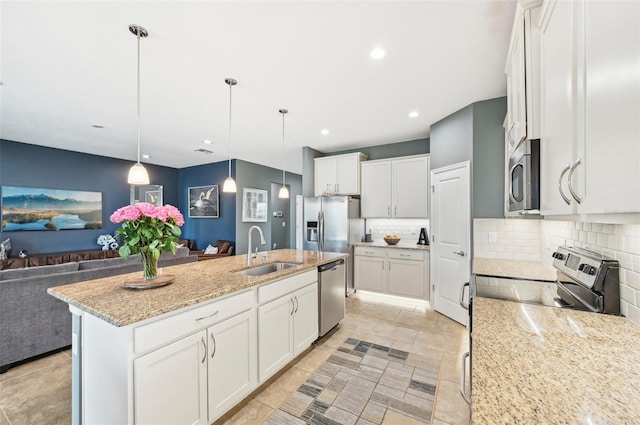 kitchen with open floor plan, decorative backsplash, appliances with stainless steel finishes, white cabinets, and a sink