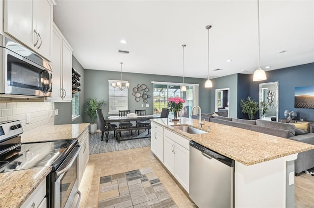 kitchen featuring decorative backsplash, stainless steel appliances, open floor plan, and a sink