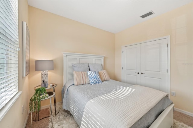 bedroom with visible vents, baseboards, carpet, and a closet