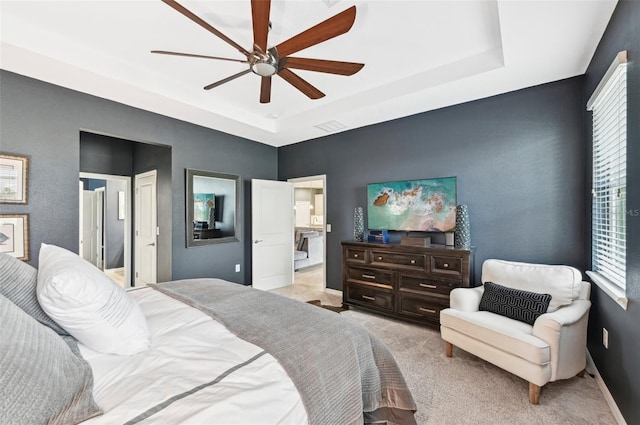 bedroom featuring visible vents, light colored carpet, a tray ceiling, and multiple windows