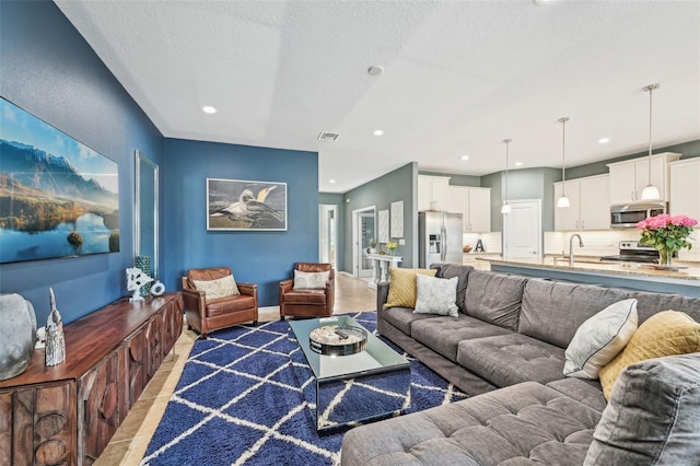 living area featuring baseboards, recessed lighting, visible vents, and a textured ceiling