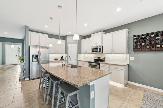 kitchen featuring light stone countertops, a breakfast bar area, decorative backsplash, stainless steel appliances, and a sink