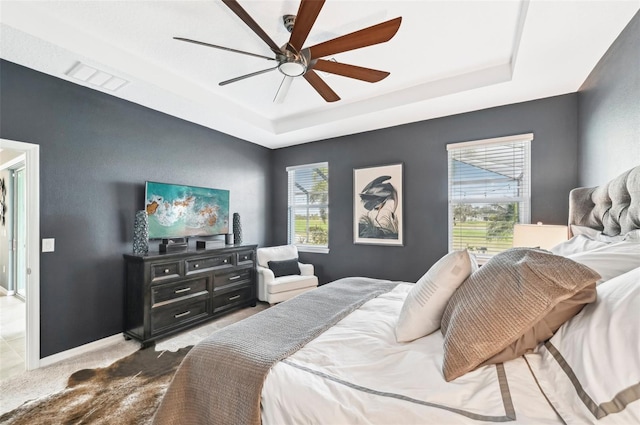 carpeted bedroom featuring visible vents, multiple windows, and a tray ceiling