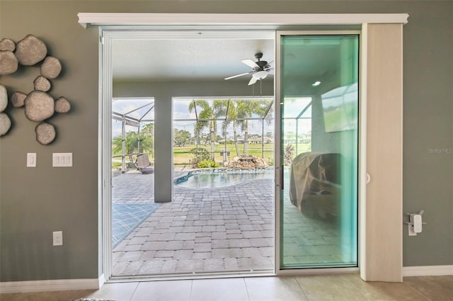 doorway with tile patterned floors, baseboards, a ceiling fan, and a sunroom