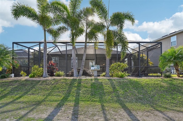 back of property featuring a lanai and a lawn