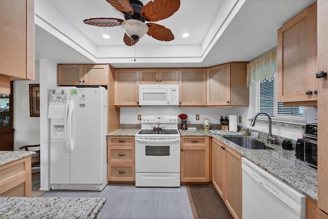 kitchen featuring sink, white appliances, ceiling fan, light stone counters, and a raised ceiling