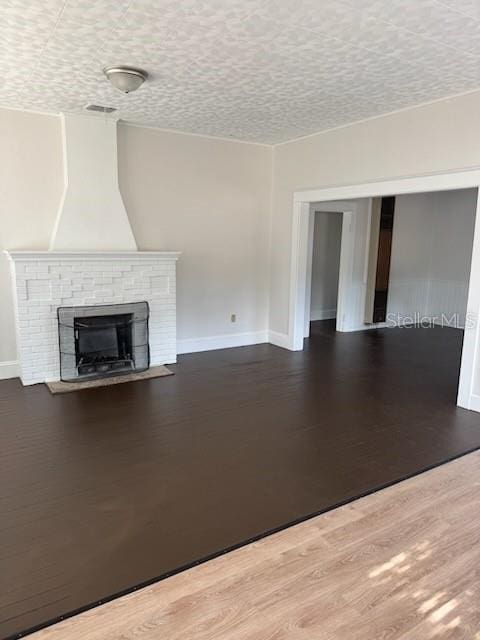 unfurnished living room with hardwood / wood-style flooring, a fireplace, and a textured ceiling