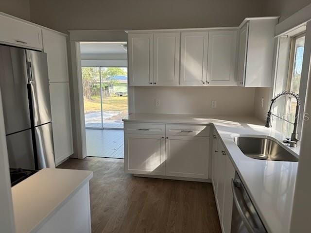 kitchen with sink, dark wood-type flooring, white cabinets, and appliances with stainless steel finishes