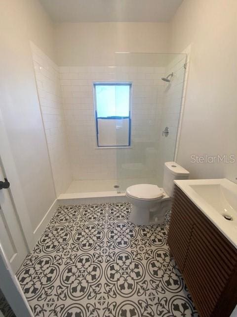 bathroom with vanity, toilet, tile patterned flooring, and a tile shower