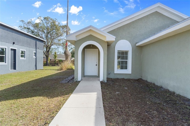 view of exterior entry featuring a lawn