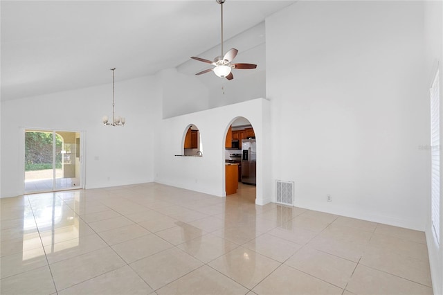 empty room featuring light tile patterned flooring, high vaulted ceiling, and ceiling fan with notable chandelier