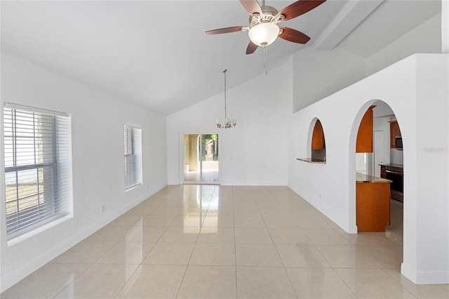 tiled empty room with ceiling fan with notable chandelier and high vaulted ceiling