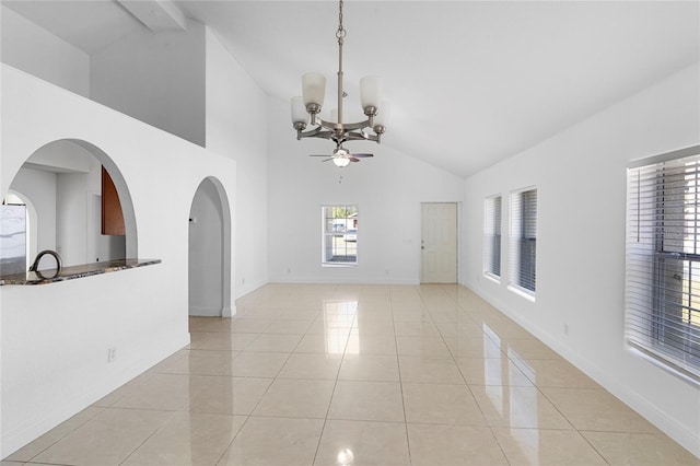 tiled empty room with ceiling fan with notable chandelier and high vaulted ceiling