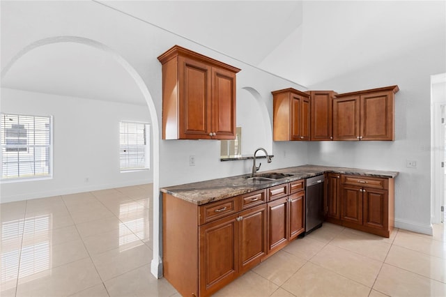 kitchen with light tile patterned flooring, vaulted ceiling, sink, dark stone counters, and stainless steel dishwasher