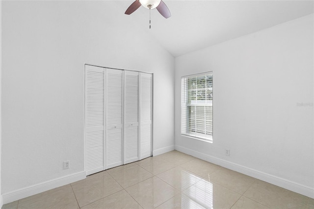 unfurnished bedroom featuring light tile patterned flooring, ceiling fan, lofted ceiling, and a closet