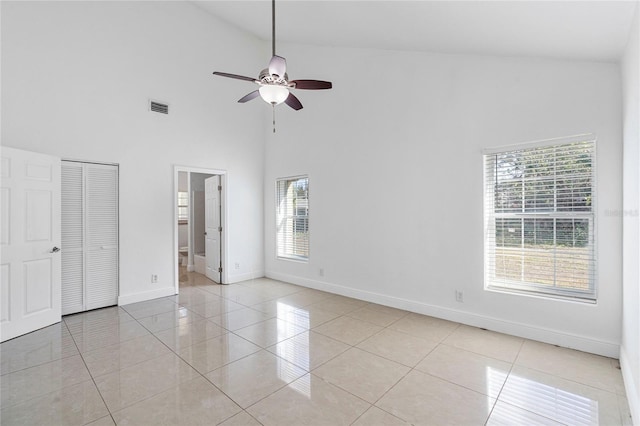 unfurnished bedroom with a high ceiling, ensuite bathroom, light tile patterned floors, and ceiling fan