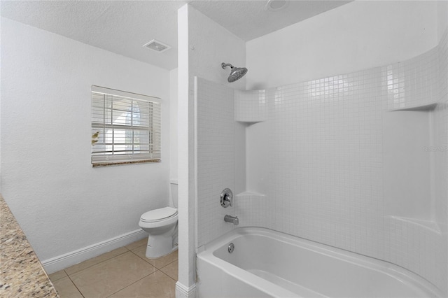 bathroom with tiled shower / bath combo, tile patterned floors, a textured ceiling, and toilet