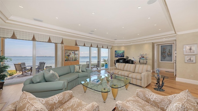 living room with a water view, a tray ceiling, crown molding, and light wood-type flooring