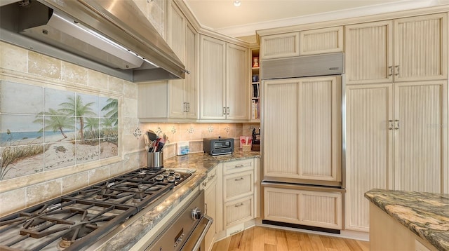 kitchen with custom exhaust hood, dark stone counters, stainless steel gas stovetop, and light wood-type flooring