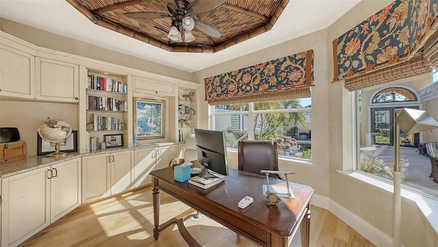 office with ceiling fan, a raised ceiling, and light hardwood / wood-style flooring