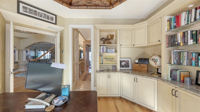 office area with light stone countertops and light wood-type flooring