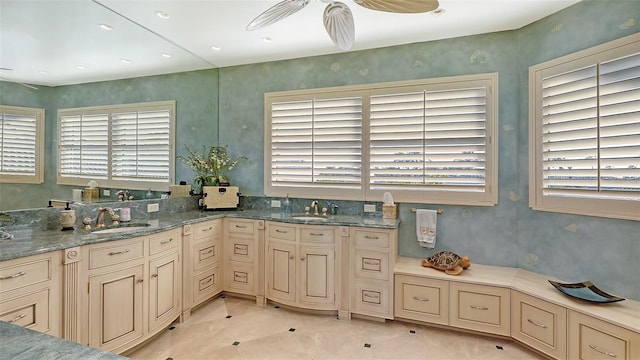 kitchen featuring ceiling fan, light stone countertops, and sink