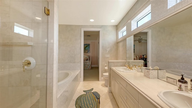 bathroom with a relaxing tiled tub, vanity, tile patterned floors, and toilet