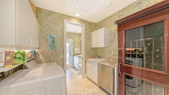 clothes washing area with cabinets, washer / dryer, and sink