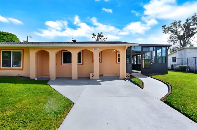 view of front of property with a carport, a sunroom, and a front yard