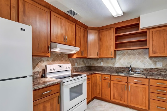 kitchen featuring fridge, sink, dark stone counters, and electric stove