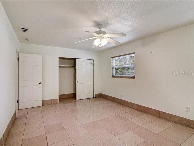 unfurnished bedroom featuring light tile patterned flooring, ceiling fan, a closet, and a textured ceiling