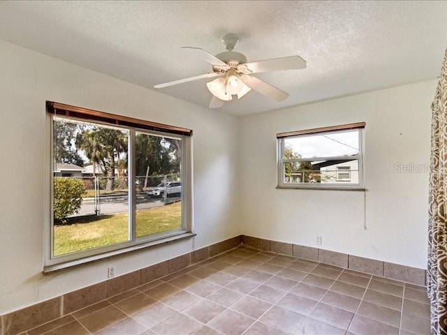 spare room featuring ceiling fan, a textured ceiling, and light tile patterned floors