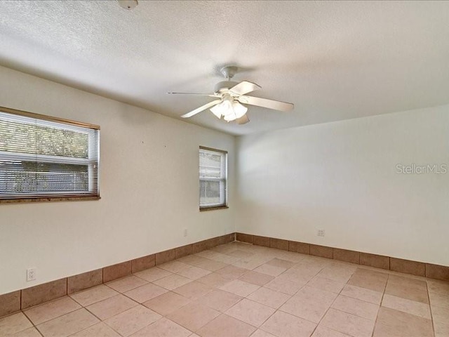 spare room with light tile patterned floors, a textured ceiling, and ceiling fan