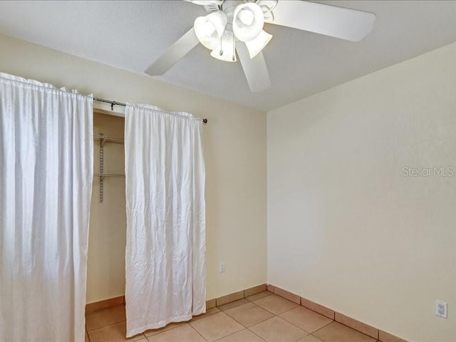 tiled spare room with ceiling fan