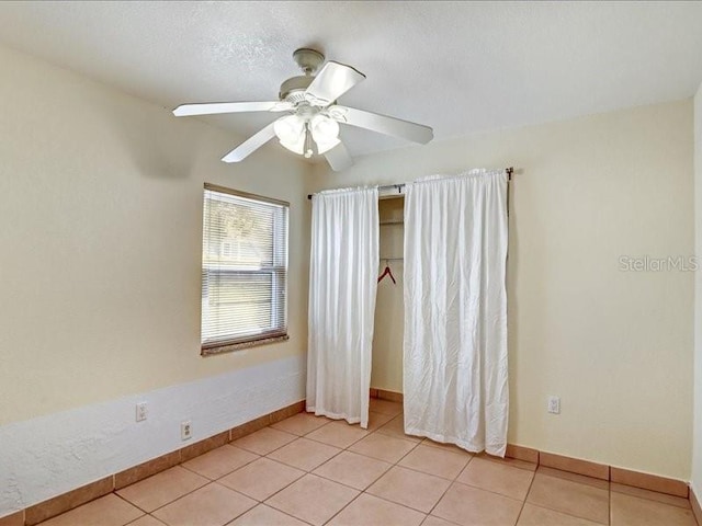 empty room featuring ceiling fan, a textured ceiling, and light tile patterned floors