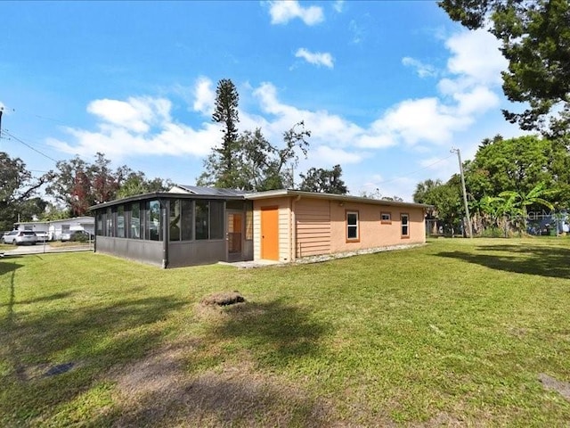 view of side of property featuring a sunroom and a lawn