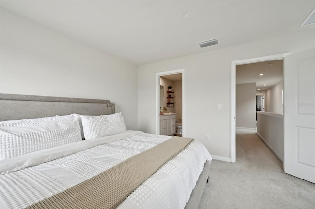 bedroom with connected bathroom and light colored carpet