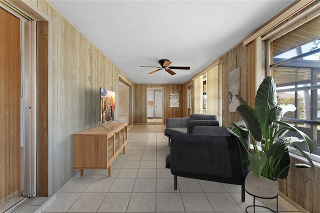 tiled living room with ceiling fan and wood walls