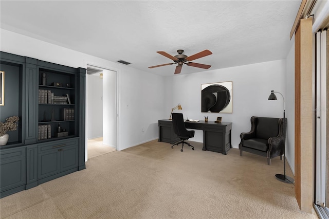 carpeted home office featuring a textured ceiling and ceiling fan