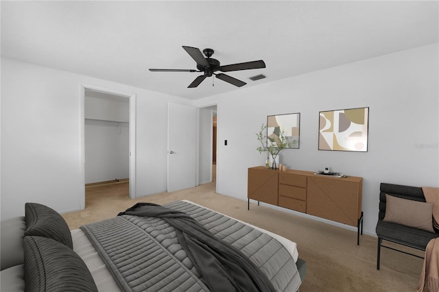 carpeted bedroom with a walk in closet, ceiling fan, and a closet