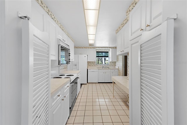 kitchen featuring white cabinetry, white appliances, light tile patterned flooring, and sink