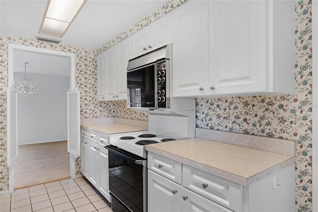 kitchen featuring light tile patterned flooring, a chandelier, electric range oven, and white cabinets