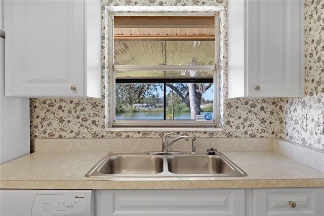 kitchen featuring white cabinetry, dishwashing machine, and sink