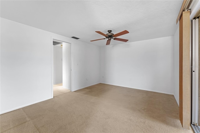 spare room featuring a textured ceiling, light colored carpet, and ceiling fan